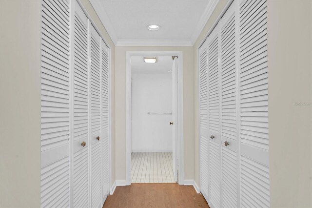 corridor with hardwood / wood-style floors and ornamental molding