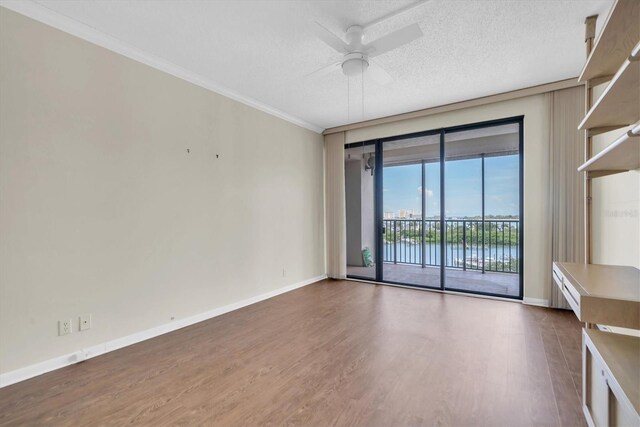 empty room featuring hardwood / wood-style flooring, a textured ceiling, a water view, and ceiling fan