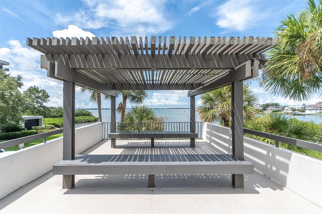 view of patio with a pergola and a water view