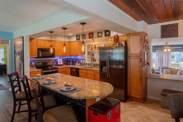 kitchen with ceiling fan, black appliances, light stone countertops, decorative backsplash, and sink