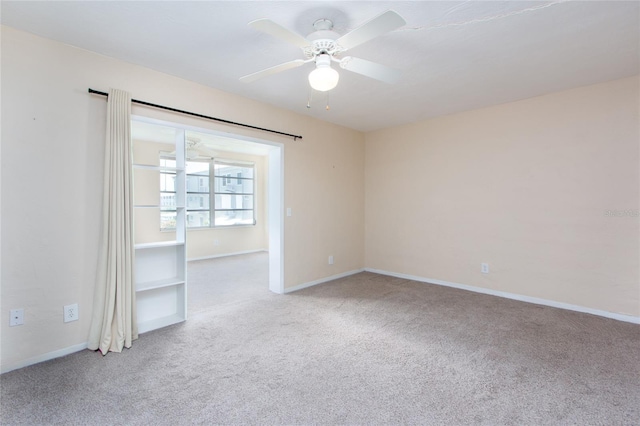 carpeted empty room featuring a ceiling fan and baseboards