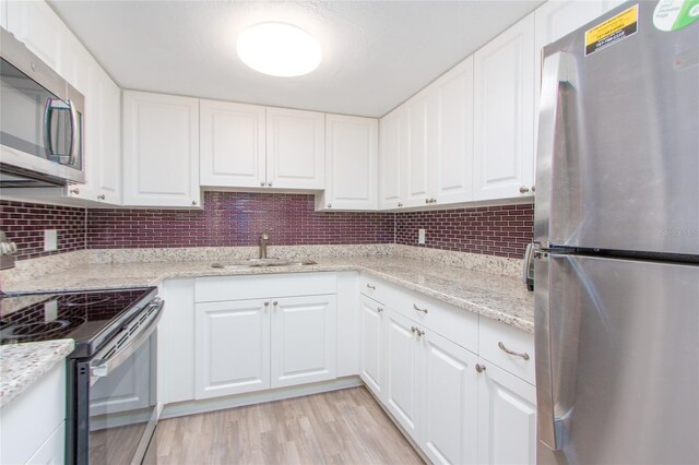 kitchen featuring white cabinets, stainless steel appliances, tasteful backsplash, and sink