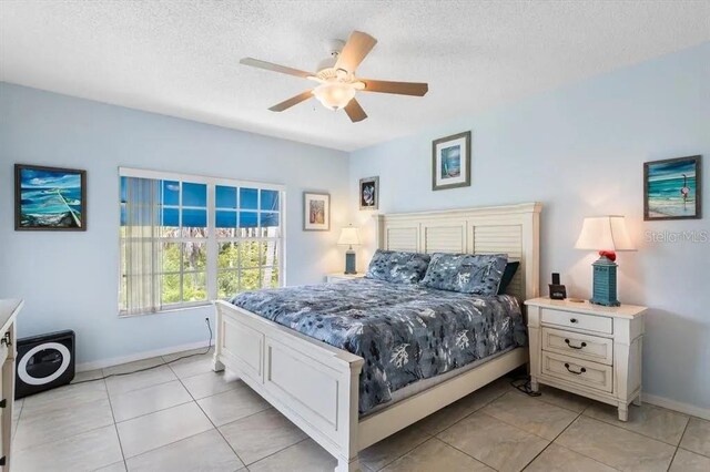 bedroom featuring ceiling fan, light tile patterned floors, and a textured ceiling