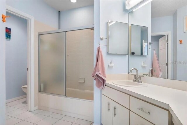 full bathroom featuring tile patterned flooring, enclosed tub / shower combo, vanity, and toilet