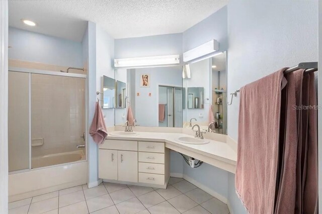 bathroom featuring vanity, bath / shower combo with glass door, tile patterned floors, and a textured ceiling