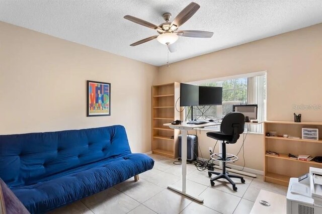 tiled office space featuring a textured ceiling and ceiling fan