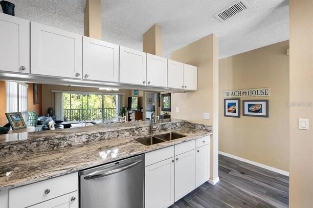 kitchen with sink, light stone counters, stainless steel dishwasher, dark hardwood / wood-style floors, and white cabinets