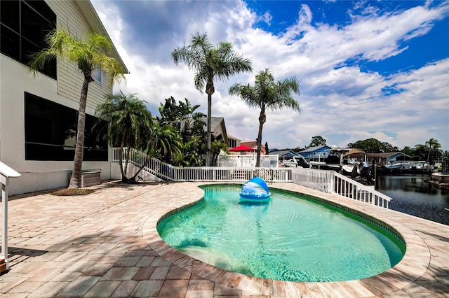 view of swimming pool featuring a water view and a patio area