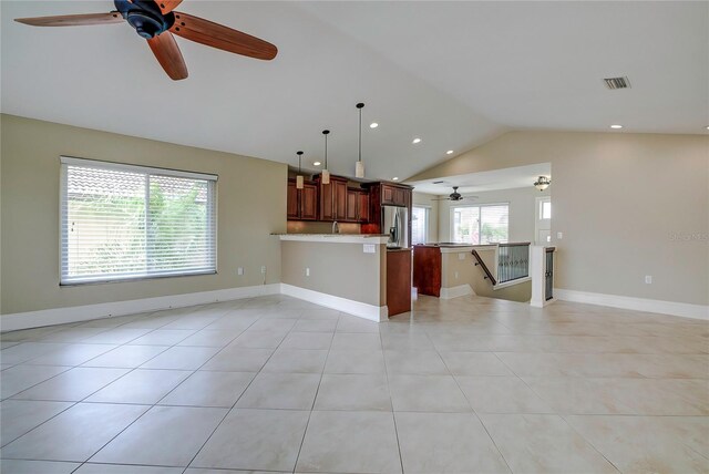 unfurnished living room featuring ceiling fan, vaulted ceiling, and light tile patterned flooring