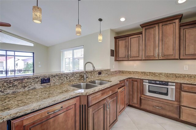 kitchen with light stone countertops, decorative light fixtures, sink, stainless steel oven, and light tile patterned flooring