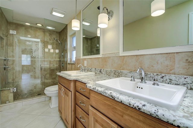 bathroom with a shower with door, tile walls, toilet, dual bowl vanity, and decorative backsplash