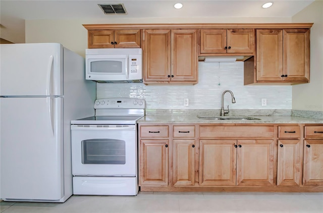 kitchen with white appliances, backsplash, light tile patterned floors, light stone counters, and sink