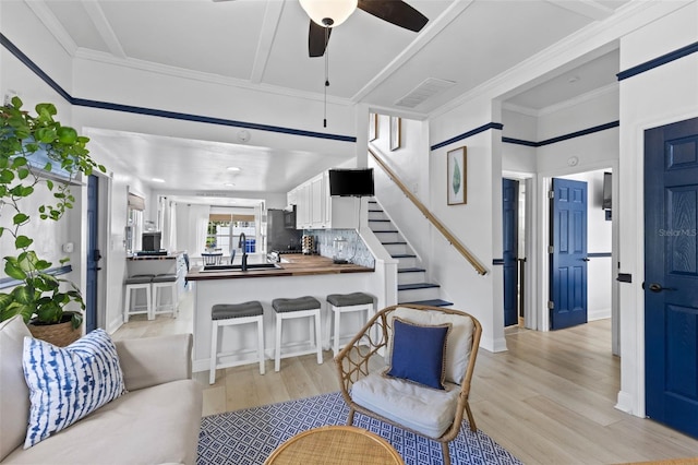 living room featuring ceiling fan, light wood-type flooring, and ornamental molding