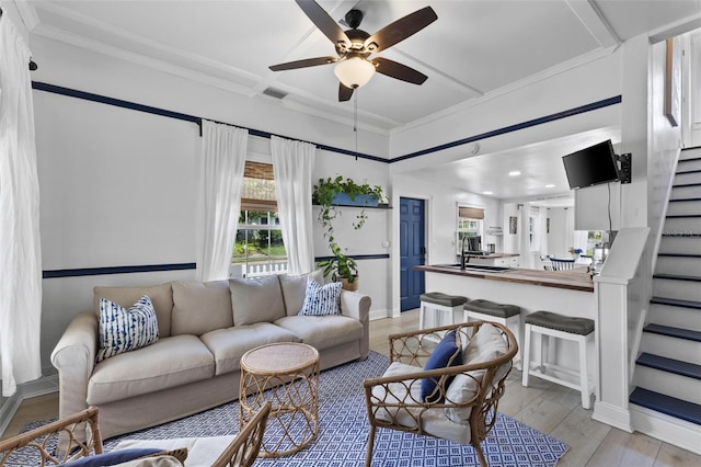 living room featuring light hardwood / wood-style flooring, crown molding, and ceiling fan