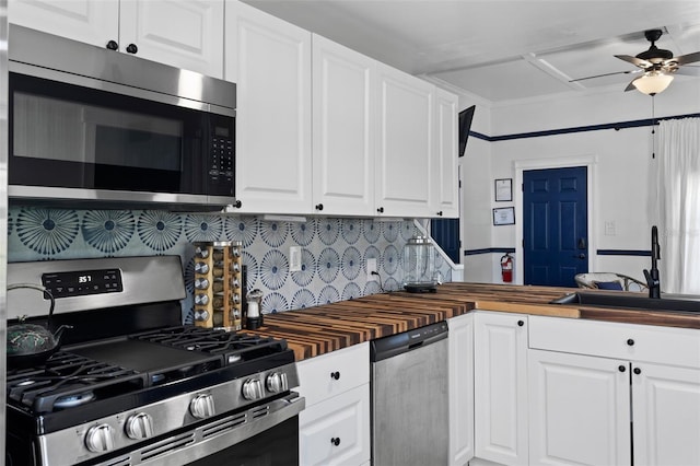 kitchen featuring ceiling fan, white cabinetry, backsplash, stainless steel appliances, and butcher block counters