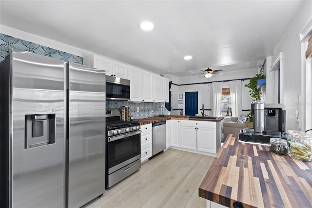 kitchen with decorative backsplash, light hardwood / wood-style flooring, ceiling fan, appliances with stainless steel finishes, and wood counters