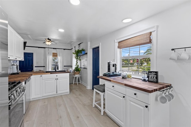 kitchen with ceiling fan, white cabinetry, wood counters, light wood-type flooring, and stainless steel appliances