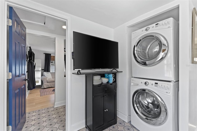 clothes washing area featuring light wood-type flooring, cabinets, and stacked washer and dryer