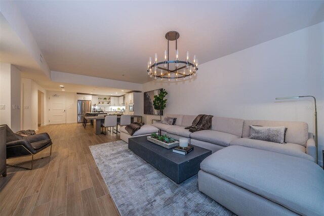 living room with light hardwood / wood-style flooring and a notable chandelier