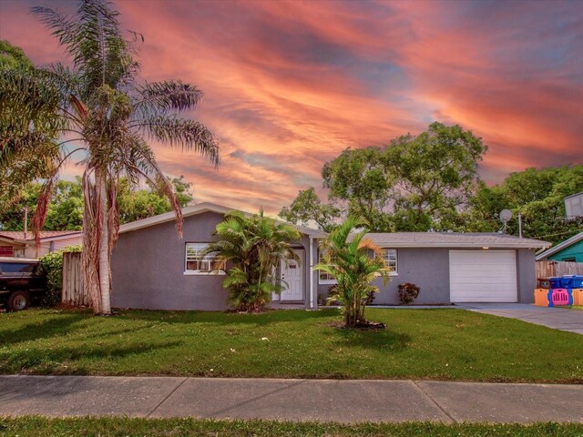 single story home with a garage and a lawn