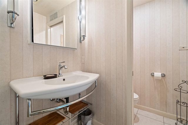 bathroom featuring visible vents, toilet, a sink, baseboards, and tile patterned floors