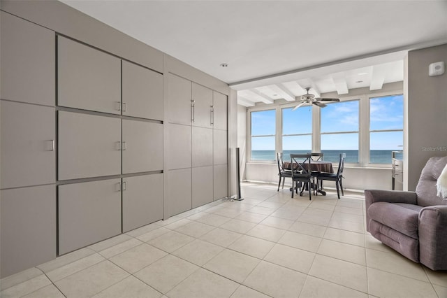 interior space featuring ceiling fan, a view of the beach, a water view, a package area, and beamed ceiling