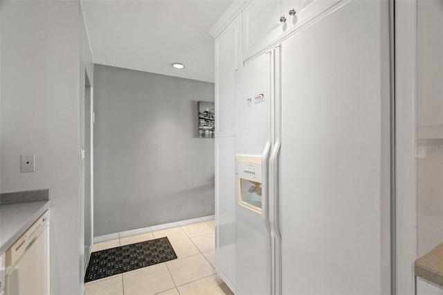 interior space featuring light tile patterned floors, light countertops, white refrigerator with ice dispenser, and white cabinets