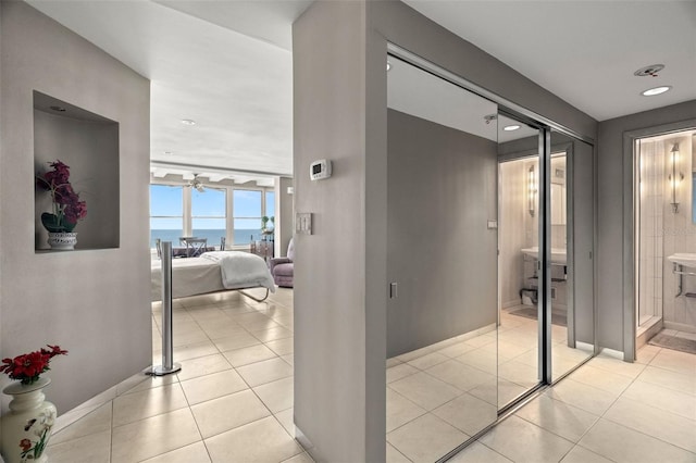 hallway with a water view, baseboards, and light tile patterned floors