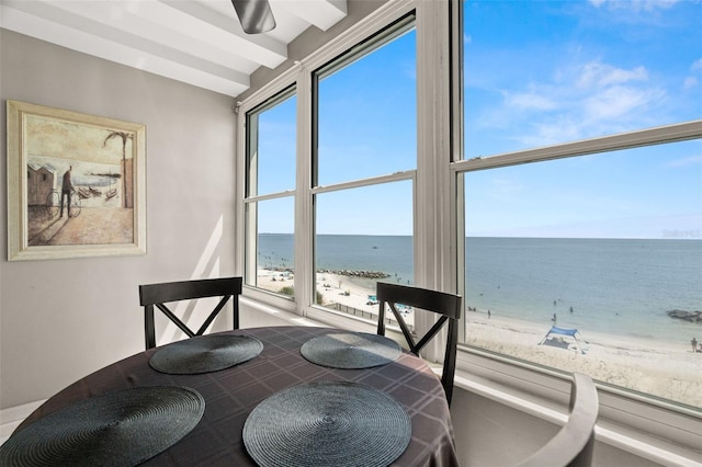 dining area featuring ceiling fan, a beach view, and a water view