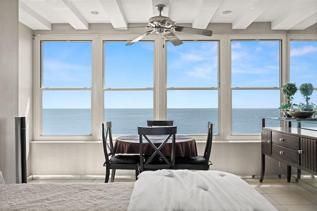 bedroom with beam ceiling, a water view, multiple windows, and light tile patterned floors