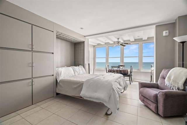 bedroom featuring light tile patterned floors, a water view, and a view of the beach