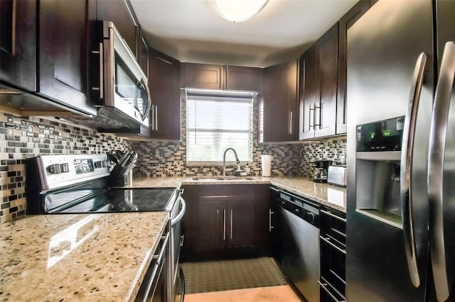 kitchen with light stone counters, stainless steel appliances, sink, dark brown cabinets, and tasteful backsplash