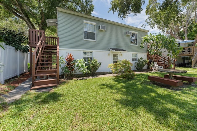 rear view of property featuring fence, stairway, a wall mounted air conditioner, and a yard