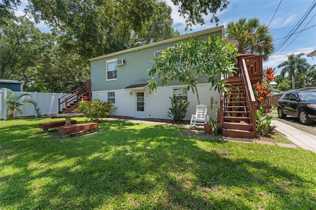 back of house featuring stairway, fence, and a lawn