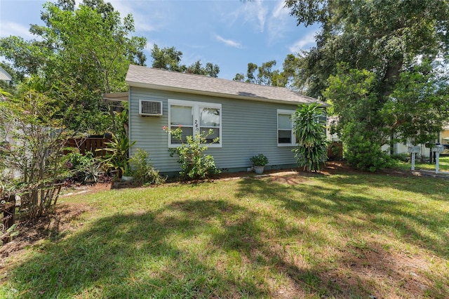 view of side of home featuring a wall mounted air conditioner, fence, and a yard