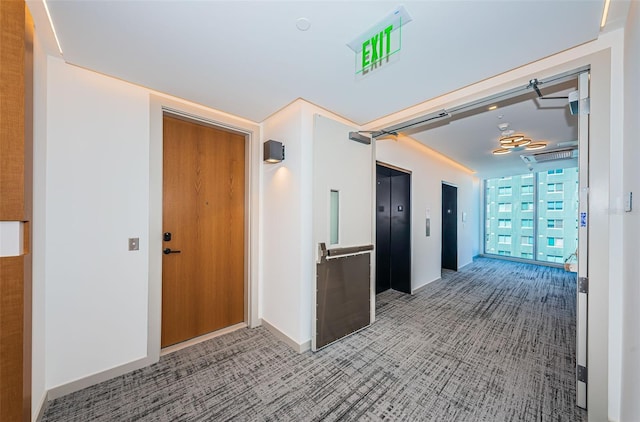 hall with carpet, elevator, and baseboards