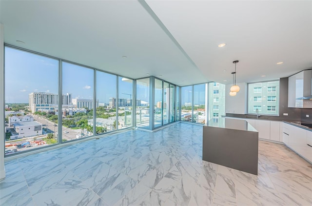 kitchen featuring pendant lighting, white cabinetry, floor to ceiling windows, and sink