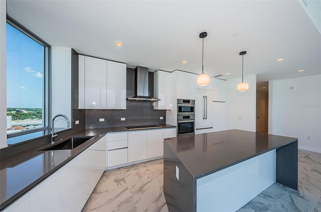 kitchen featuring pendant lighting, a center island, wall chimney range hood, and white cabinetry