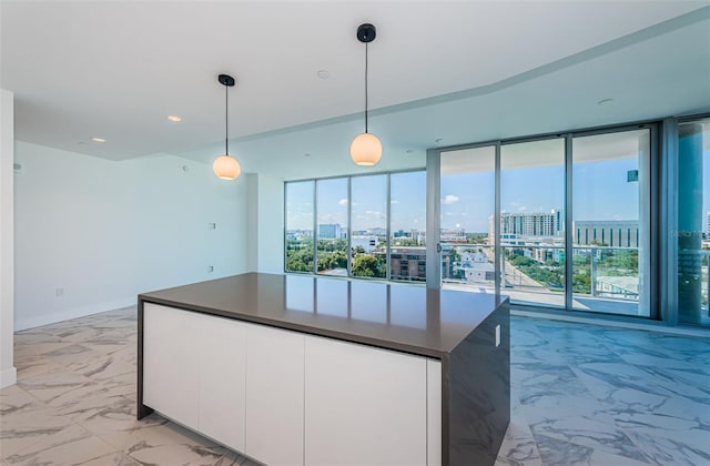 kitchen with white cabinets, a wall of windows, and hanging light fixtures