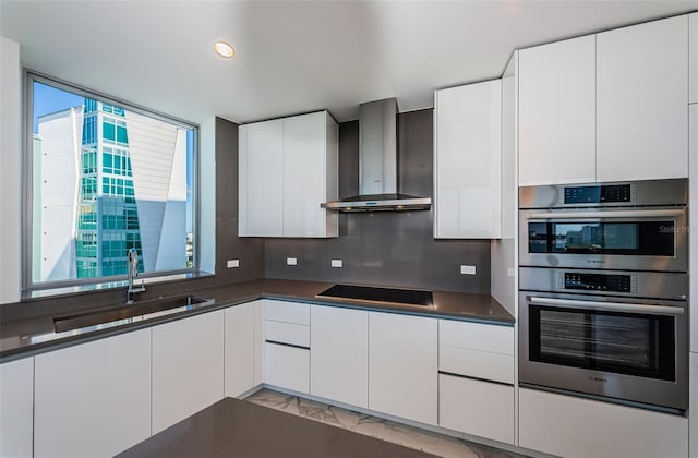 kitchen featuring white cabinets, stovetop, and wall chimney exhaust hood