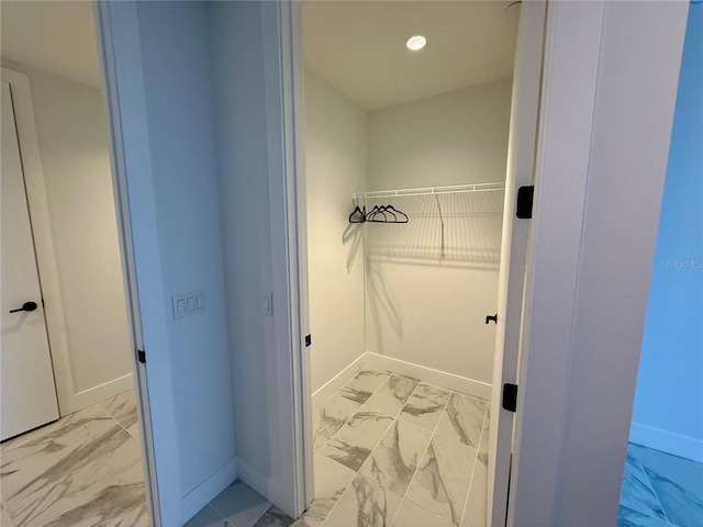 walk in closet featuring marble finish floor