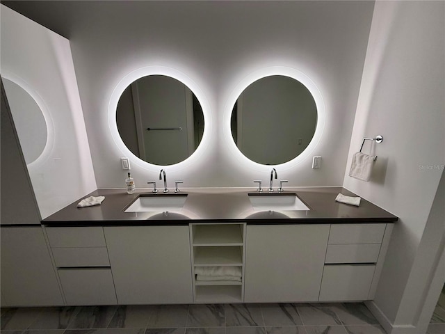 bathroom featuring double vanity, marble finish floor, and a sink