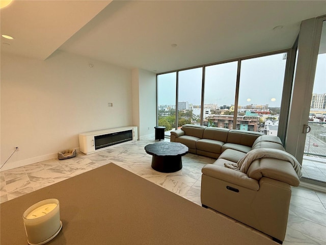 living area with a city view, baseboards, marble finish floor, a wall of windows, and a glass covered fireplace