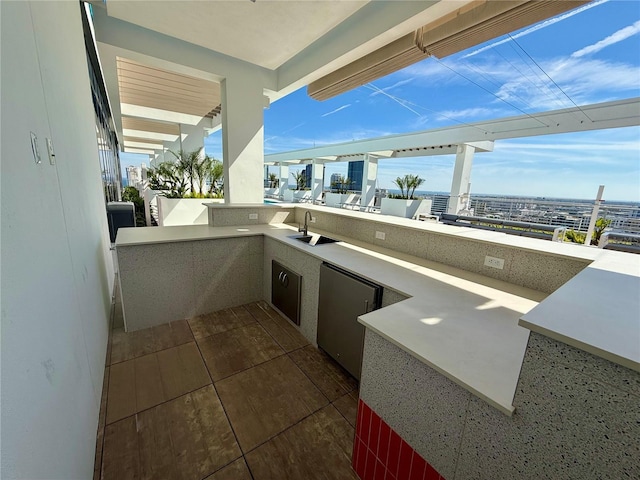 view of patio featuring exterior kitchen, a view of city, and a sink