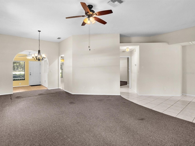 unfurnished living room with light carpet, light tile patterned floors, visible vents, arched walkways, and ceiling fan with notable chandelier