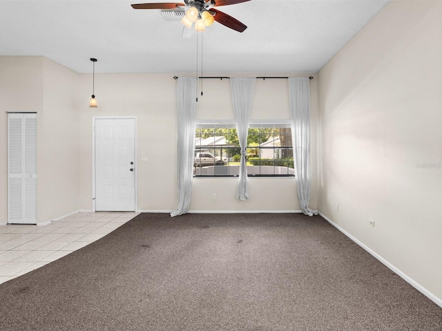 spare room featuring light tile patterned floors, baseboards, a ceiling fan, and light colored carpet