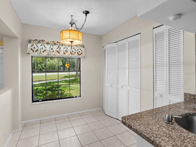 kitchen featuring light tile patterned flooring, hanging light fixtures, and a textured ceiling