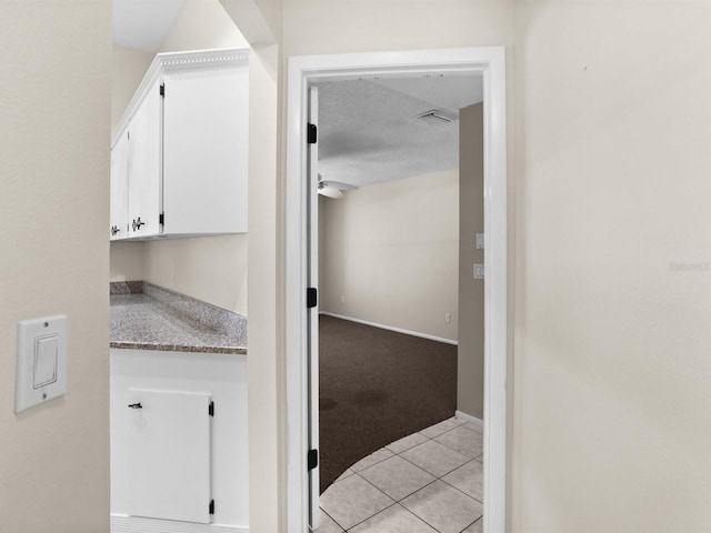 interior space featuring light tile patterned floors, a textured ceiling, light colored carpet, visible vents, and baseboards