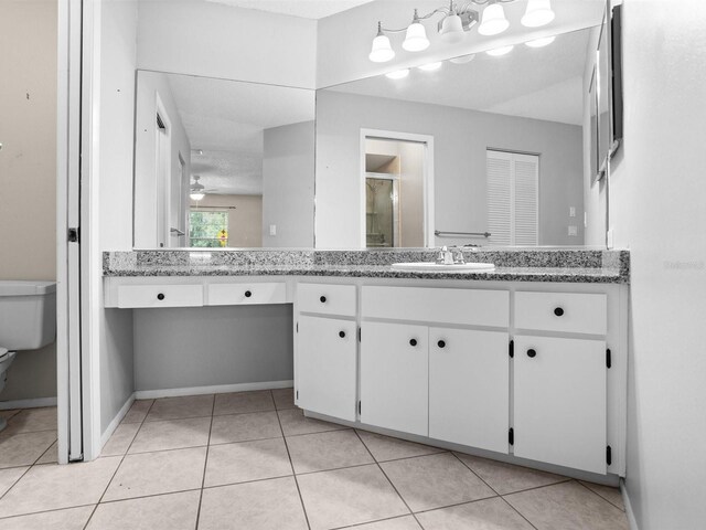 bathroom with tile patterned floors, toilet, vanity, and ceiling fan