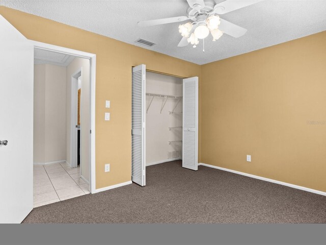 unfurnished bedroom with a textured ceiling, light carpet, ceiling fan, and a closet